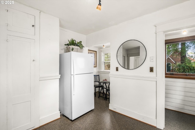 kitchen with freestanding refrigerator, healthy amount of natural light, and baseboards