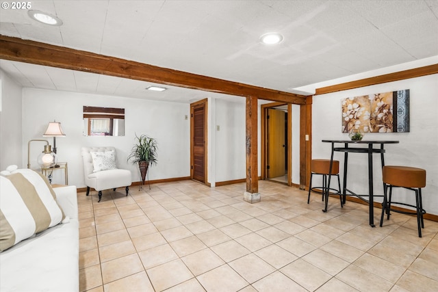 living room featuring baseboards, light tile patterned floors, and beam ceiling