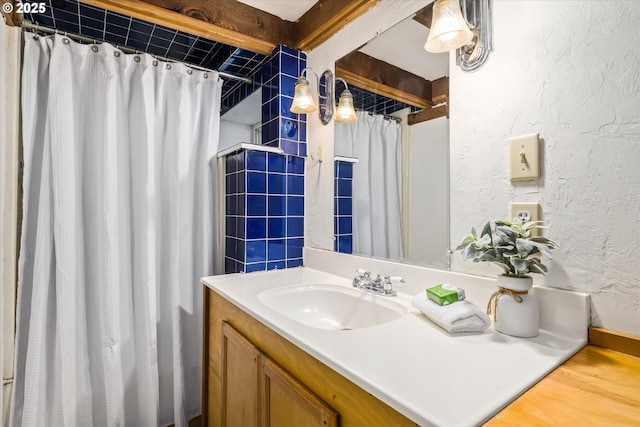 bathroom with a textured wall, vanity, and a shower with curtain