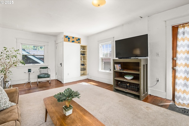 living area with healthy amount of natural light, wood finished floors, and baseboards