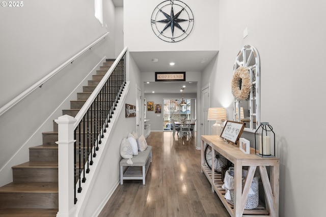 foyer entrance with stairway, a high ceiling, baseboards, and wood finished floors