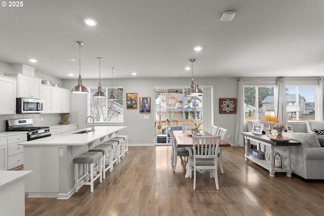 dining area featuring recessed lighting, wood finished floors, baseboards, and a healthy amount of sunlight