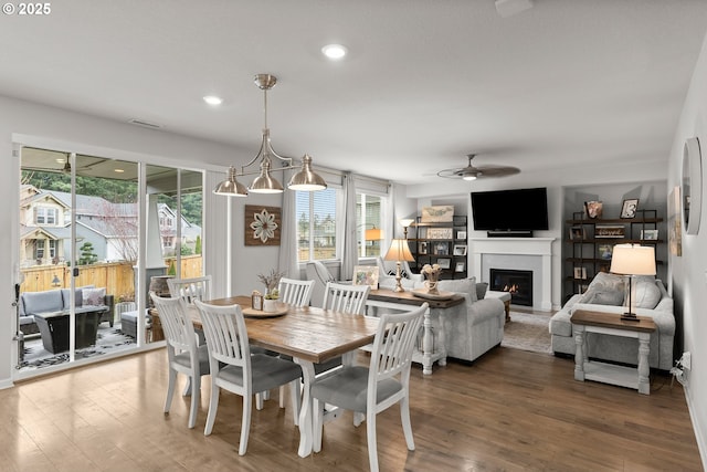 dining space featuring a glass covered fireplace, recessed lighting, ceiling fan, and wood finished floors