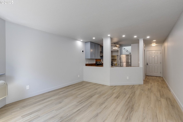 unfurnished living room featuring baseboards, light wood-type flooring, a ceiling fan, and recessed lighting