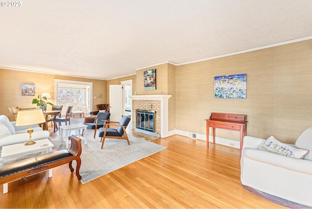 living area with a brick fireplace, light wood-style flooring, and crown molding