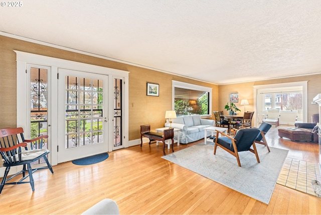 living area featuring a textured ceiling, crown molding, and light wood finished floors