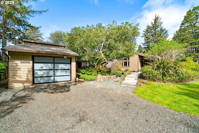 view of front of home featuring a detached garage, an outbuilding, and gravel driveway