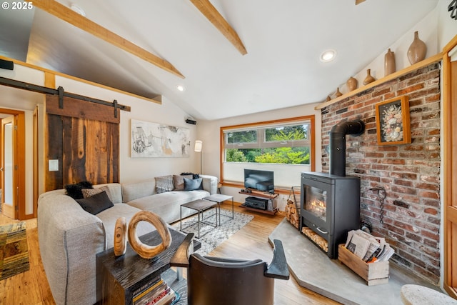 living area with a barn door, a wood stove, recessed lighting, vaulted ceiling with beams, and light wood-type flooring
