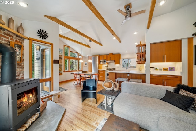 living room featuring light wood-style floors, ceiling fan, beam ceiling, and a healthy amount of sunlight
