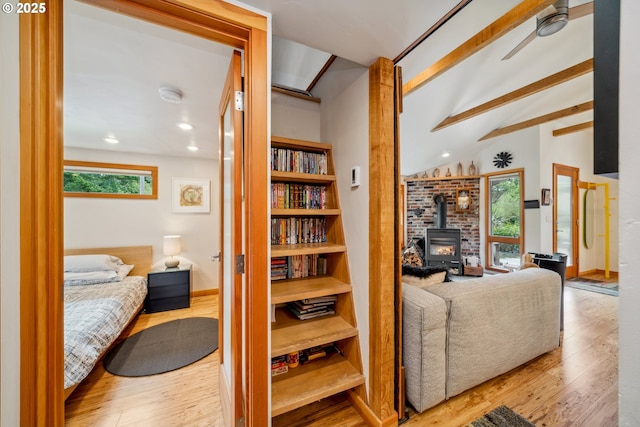 interior space with vaulted ceiling with beams, a wood stove, wood finished floors, and recessed lighting