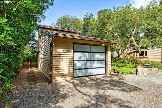 view of outdoor structure with fence, driveway, and an outdoor structure