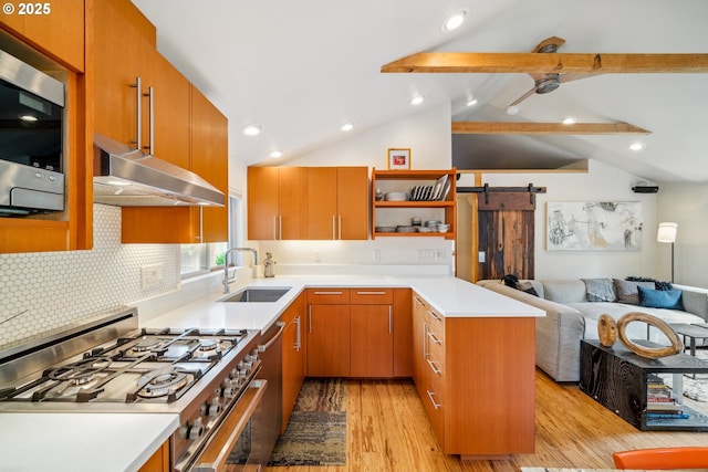 kitchen with a sink, a peninsula, open floor plan, stainless steel appliances, and light wood-style flooring