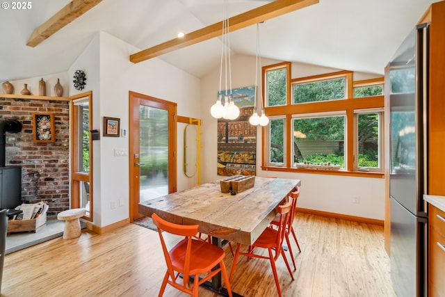 dining room with a wood stove, baseboards, lofted ceiling with beams, an inviting chandelier, and light wood-style flooring