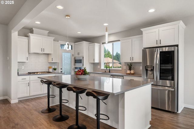 17085 SE Troge Rd, Happy Valley, OR 97086 - kitchen featuring appliances with stainless steel finishes, a center island, white cabinets, tasteful backsplash, and dark wood finished floors