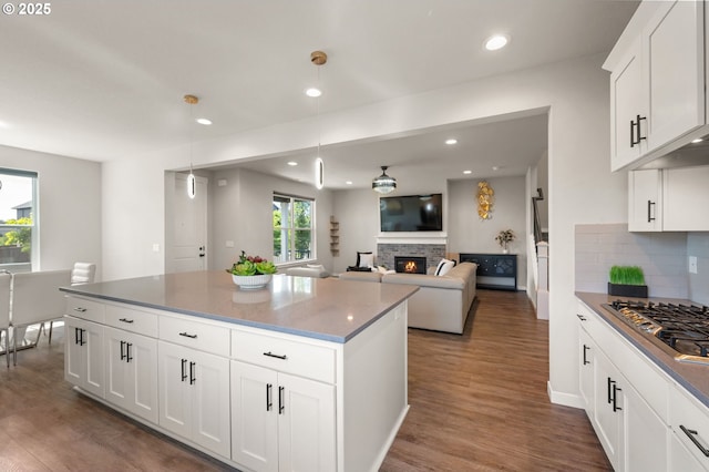 17085 SE Troge Rd, Happy Valley, OR 97086 - kitchen featuring stainless steel gas stovetop, a fireplace, dark wood-style flooring, decorative backsplash, and a kitchen island