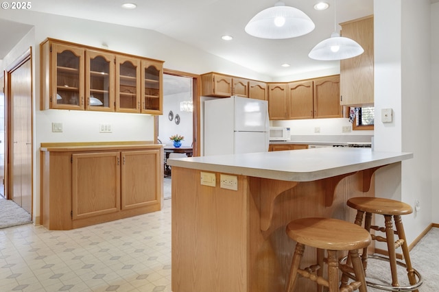 kitchen with lofted ceiling, pendant lighting, white appliances, and kitchen peninsula