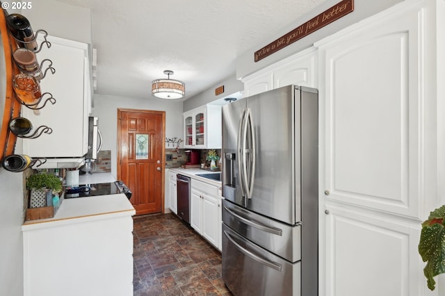 kitchen featuring stainless steel appliances, stone finish flooring, white cabinets, light countertops, and tasteful backsplash