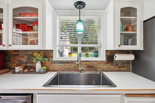 kitchen featuring a sink, stainless steel dishwasher, white cabinets, and glass insert cabinets