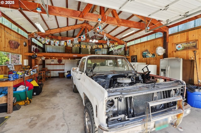 garage featuring wood walls and stainless steel fridge