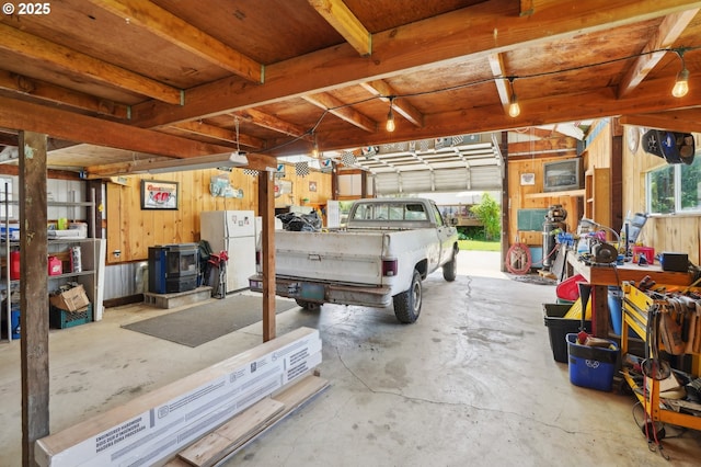 garage with freestanding refrigerator and wood walls