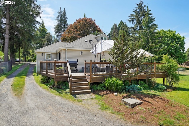 rear view of house with fence, a deck, and a shingled roof