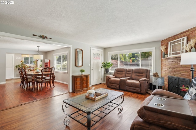 living room featuring a textured ceiling, plenty of natural light, hardwood / wood-style floors, and baseboards