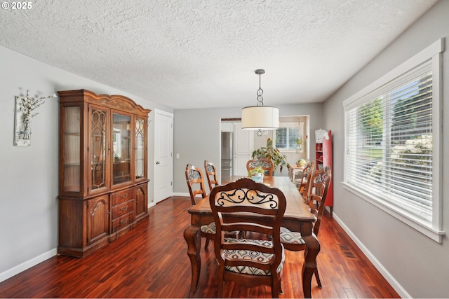 dining area with dark wood-type flooring, a textured ceiling, and baseboards