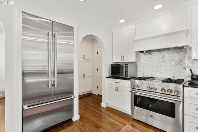2917 Westview Cir, Lake Oswego, OR 97034 - kitchen with premium appliances, arched walkways, dark countertops, dark wood-style flooring, and white cabinets