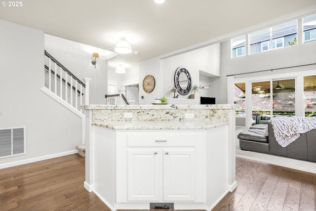 kitchen featuring light stone countertops, white cabinetry, visible vents, and wood finished floors