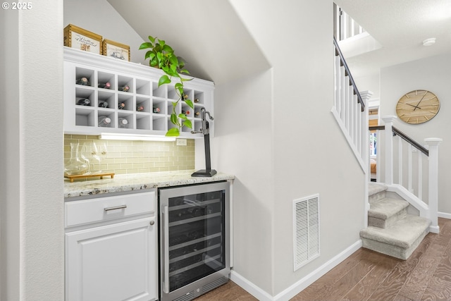 bar featuring a dry bar, visible vents, decorative backsplash, wine cooler, and wood finished floors