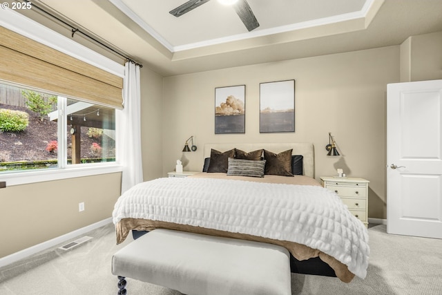 bedroom featuring a raised ceiling, light colored carpet, visible vents, ornamental molding, and baseboards