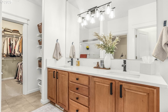 bathroom with tile patterned floors, a sink, a spacious closet, and double vanity