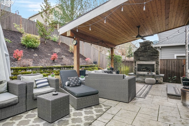 view of patio featuring a ceiling fan, a fenced backyard, and an outdoor living space with a fireplace