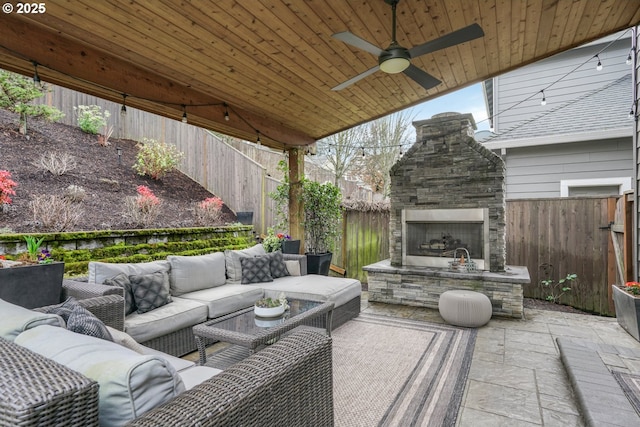 view of patio with a fenced backyard, ceiling fan, and an outdoor living space with a fireplace