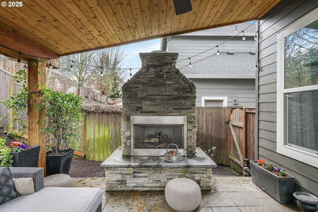 view of patio / terrace featuring an outdoor stone fireplace and fence