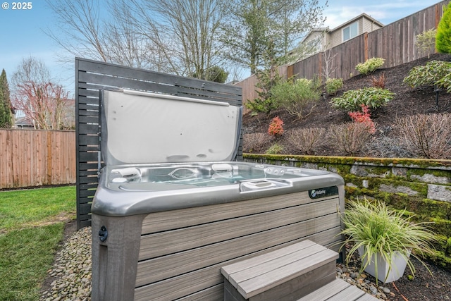 wooden deck featuring a hot tub, a fenced backyard, and an outbuilding