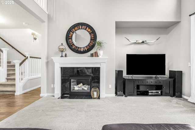 living room with carpet floors, a fireplace, baseboards, and stairs