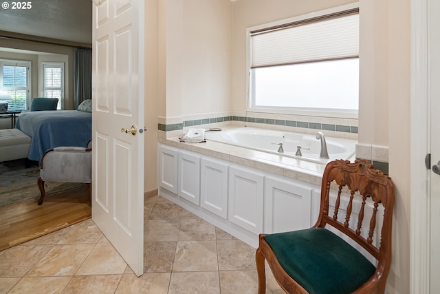 bathroom featuring tile patterned floors, a bathtub, a textured ceiling, and a wealth of natural light