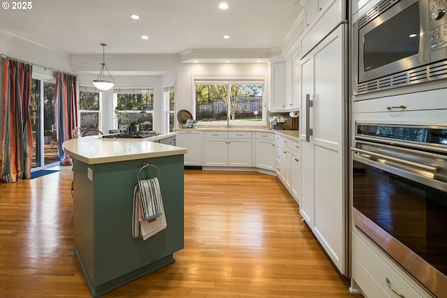 kitchen with white cabinetry, pendant lighting, stainless steel appliances, and light wood-type flooring