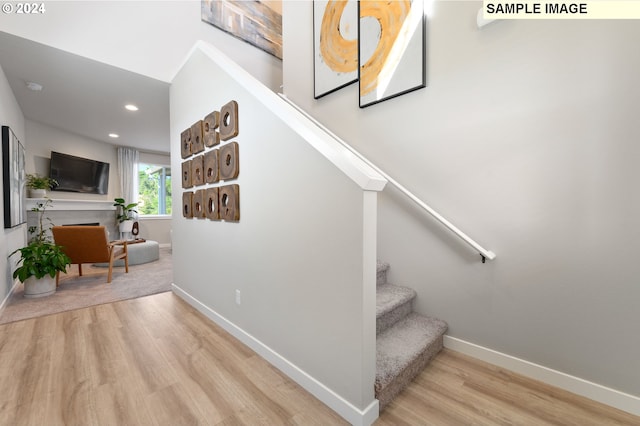 stairs featuring a fireplace and wood-type flooring