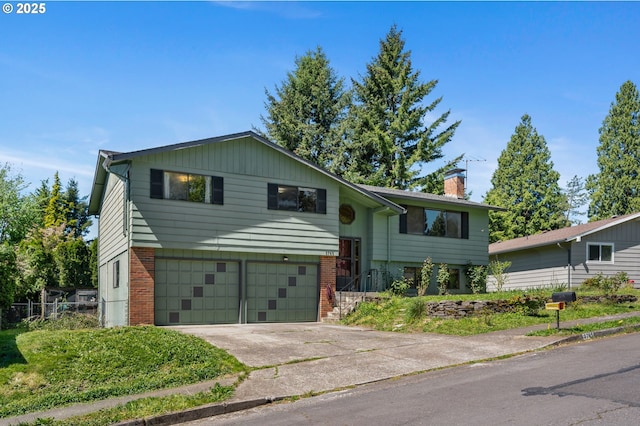 split foyer home featuring a chimney, a garage, brick siding, and driveway