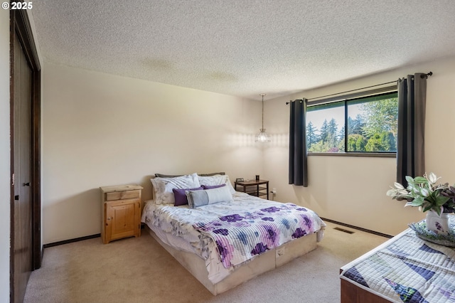 bedroom with light carpet, a textured ceiling, and baseboards