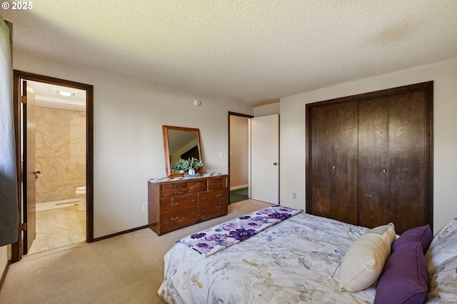 bedroom with a closet, light colored carpet, a textured ceiling, ensuite bathroom, and baseboards