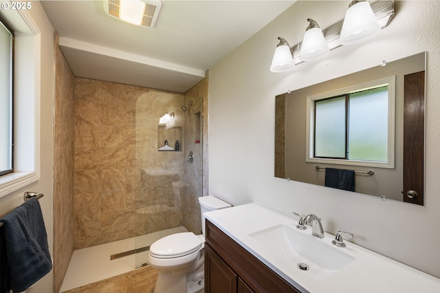 bathroom featuring tiled shower, toilet, and vanity