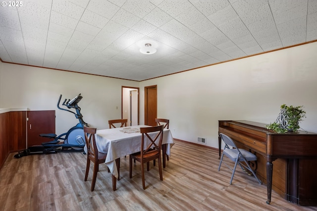 dining space featuring ornamental molding and wood finished floors