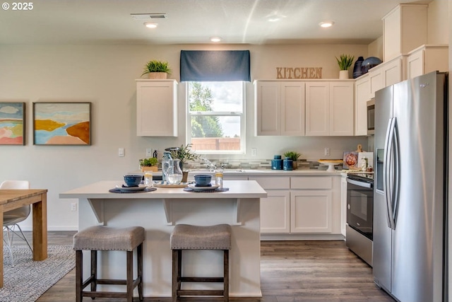 2969 U St, Springfield, OR 97477 - kitchen featuring stainless steel appliances, a kitchen island, a kitchen breakfast bar, light countertops, and dark wood-type flooring