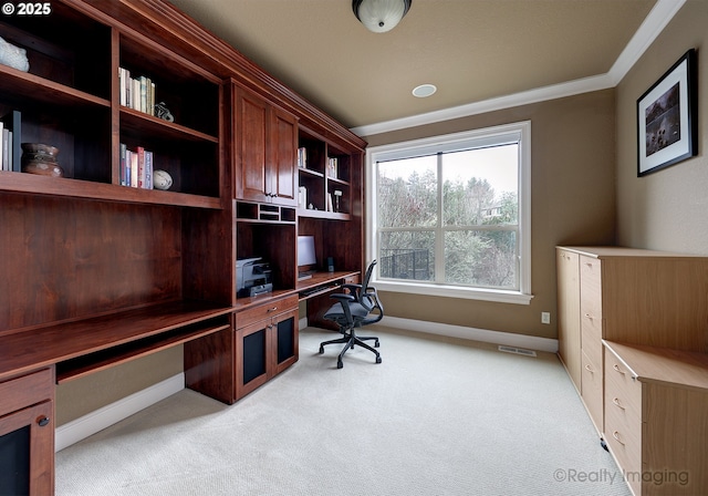 home office featuring ornamental molding, built in desk, and light carpet