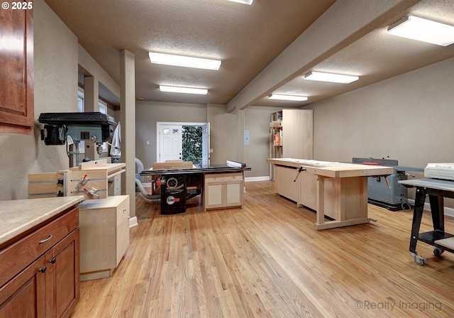 kitchen with a textured ceiling, light countertops, light wood-type flooring, and baseboards