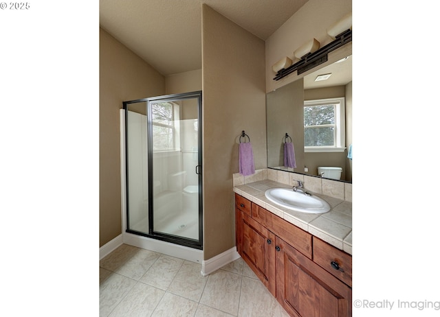 bathroom with a shower with door, vanity, tile patterned flooring, and toilet