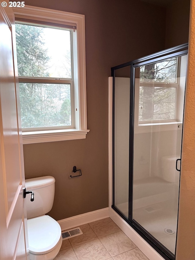 bathroom with tile patterned flooring, toilet, and walk in shower